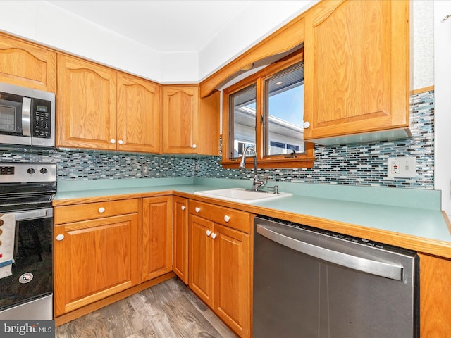 kitchen featuring light hardwood / wood-style floors, tasteful backsplash, appliances with stainless steel finishes, and sink