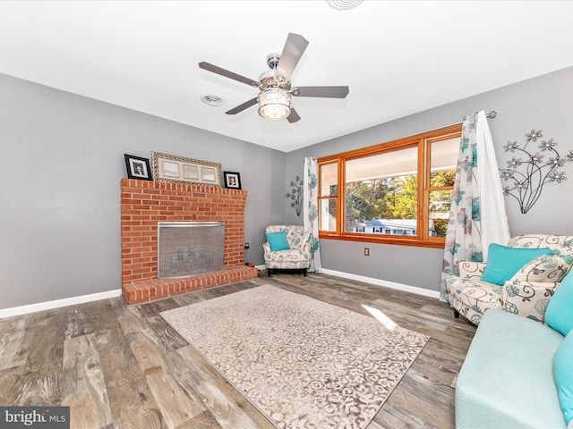 sitting room featuring ceiling fan, a brick fireplace, and dark hardwood / wood-style floors