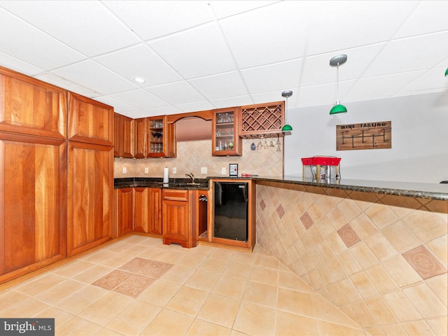 kitchen featuring light tile patterned floors, decorative light fixtures, dark stone counters, and beverage cooler