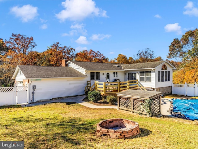 back of house with a deck, a lawn, and an outdoor fire pit