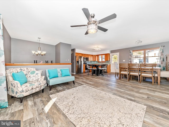 living room with light hardwood / wood-style flooring and ceiling fan with notable chandelier