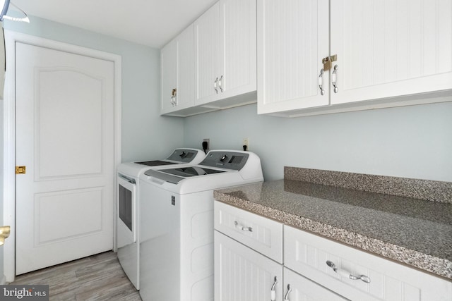 clothes washing area with light hardwood / wood-style flooring, washing machine and clothes dryer, and cabinets