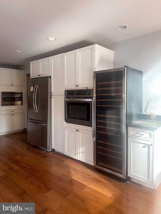 kitchen with white cabinetry, appliances with stainless steel finishes, light hardwood / wood-style flooring, and beverage cooler