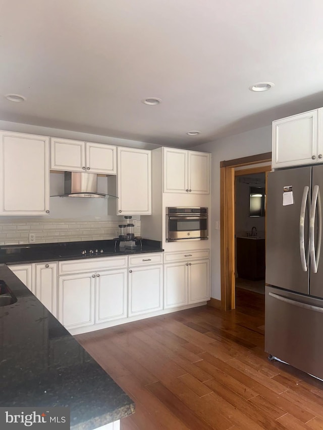 kitchen featuring appliances with stainless steel finishes, white cabinetry, backsplash, and dark hardwood / wood-style flooring