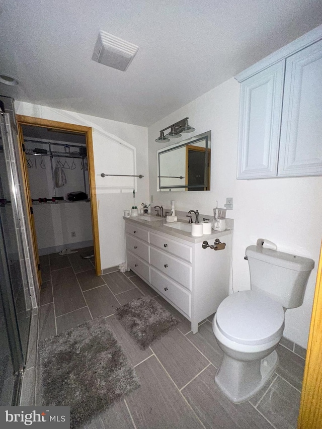 bathroom featuring vanity, an enclosed shower, a textured ceiling, and toilet