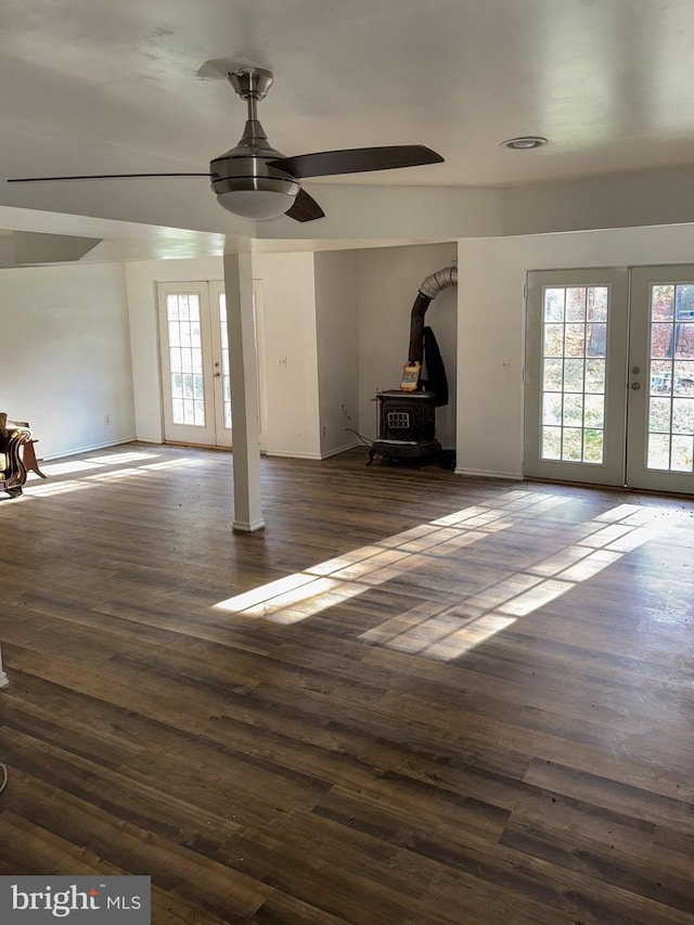 unfurnished living room with dark wood-type flooring, ceiling fan, a wood stove, and french doors