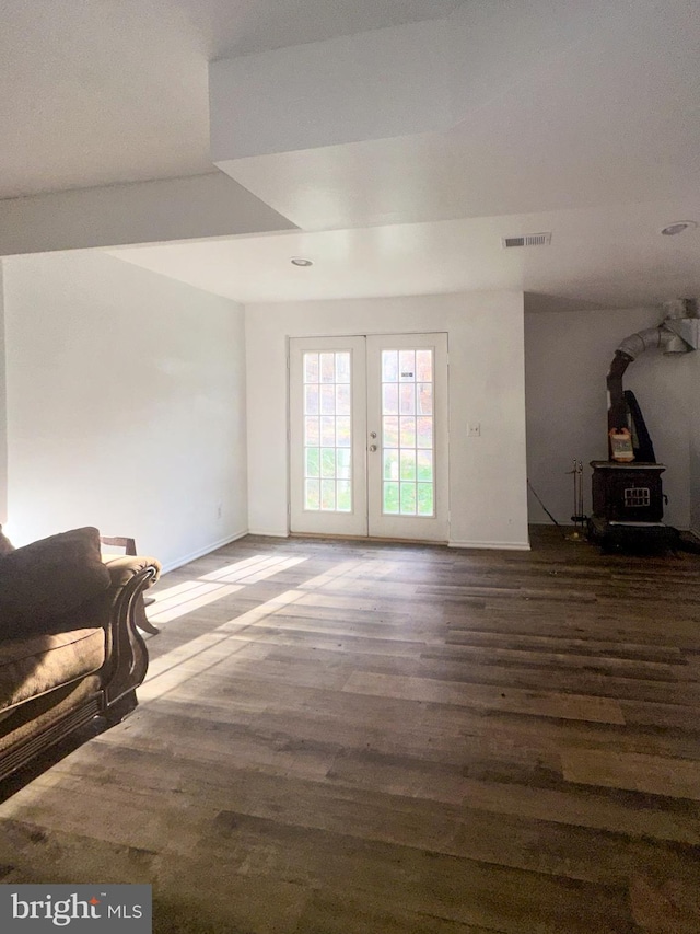 unfurnished living room featuring dark wood-type flooring, a wood stove, and french doors