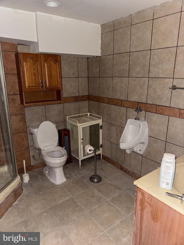 bathroom with tile walls, a shower with shower door, toilet, and tile patterned flooring