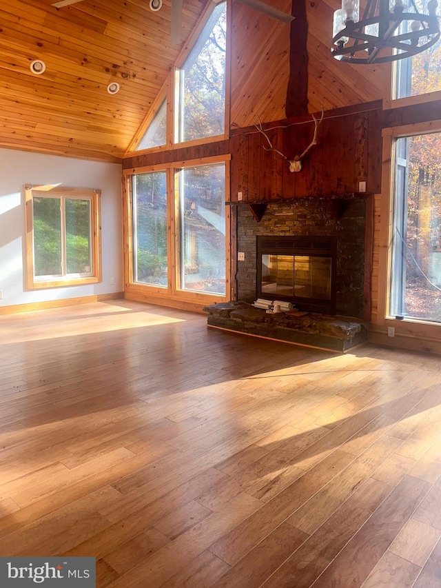 unfurnished living room featuring hardwood / wood-style floors, a stone fireplace, high vaulted ceiling, and wood ceiling