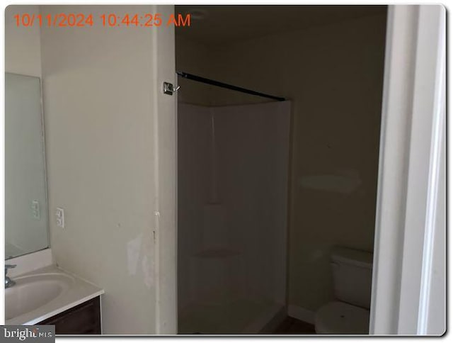 bathroom featuring walk in shower, vanity, and toilet