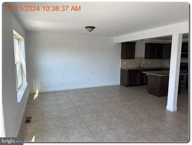 kitchen featuring light tile patterned floors, dark brown cabinetry, and tasteful backsplash