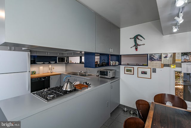 kitchen with kitchen peninsula, stainless steel appliances, sink, and light tile patterned flooring