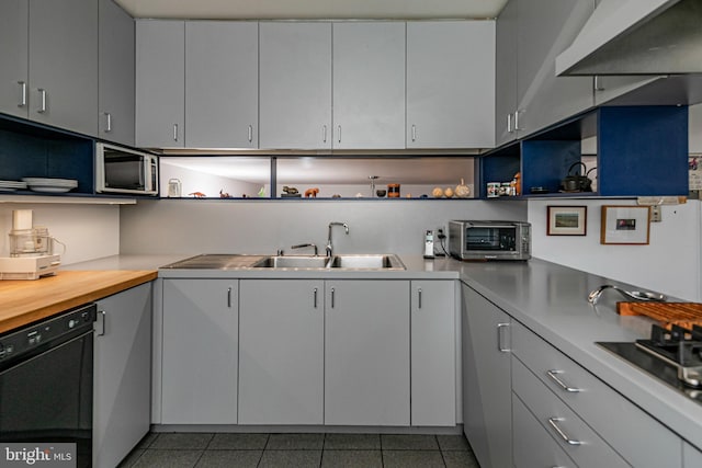 kitchen with dark tile patterned floors, sink, butcher block countertops, and stainless steel appliances