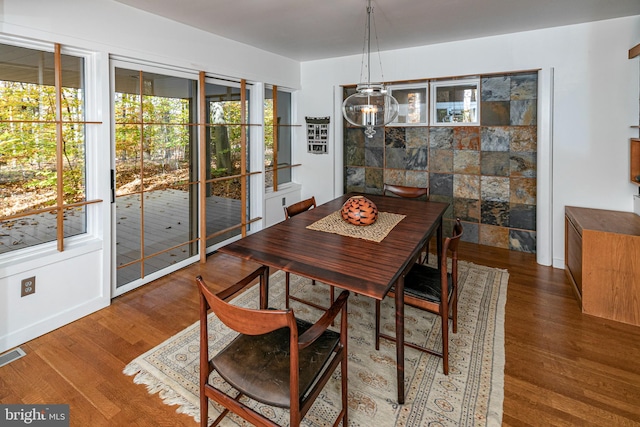 dining area featuring dark wood-type flooring and tile walls