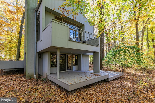 back of property with a deck and a balcony