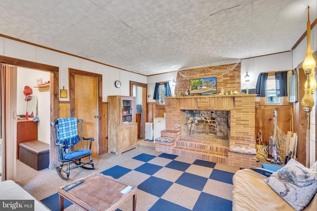 living area with wood walls, radiator, ornamental molding, a brick fireplace, and carpet floors