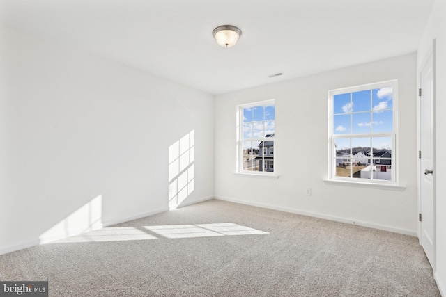 empty room with light carpet, visible vents, and baseboards