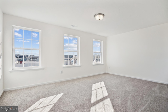 carpeted spare room featuring visible vents and baseboards