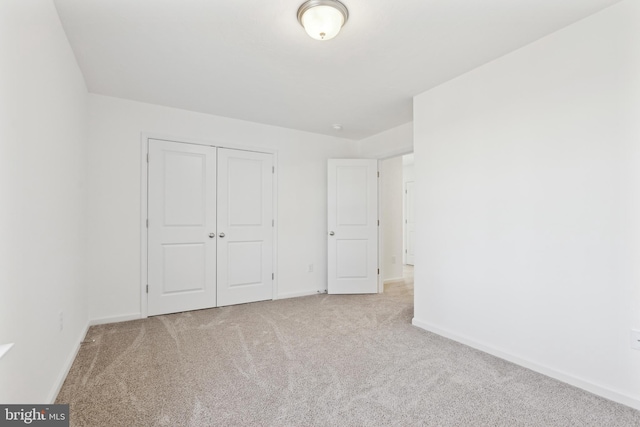 unfurnished bedroom with baseboards, a closet, and light colored carpet