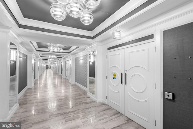 hallway featuring ornamental molding, a chandelier, and a tray ceiling