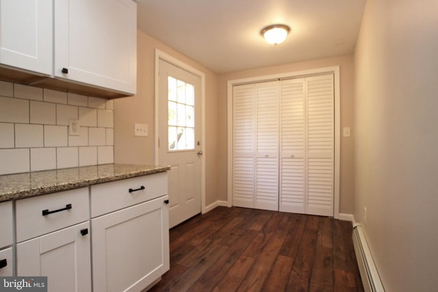 kitchen with decorative backsplash, dark wood-type flooring, a baseboard radiator, white cabinets, and light stone counters