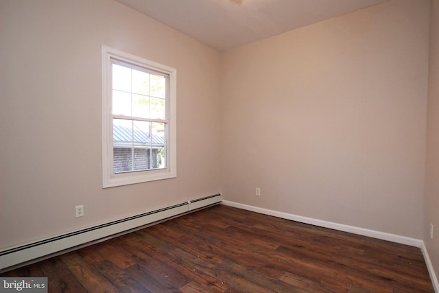 spare room featuring a baseboard heating unit and dark hardwood / wood-style flooring