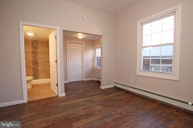 unfurnished bedroom with baseboard heating, connected bathroom, and dark hardwood / wood-style floors