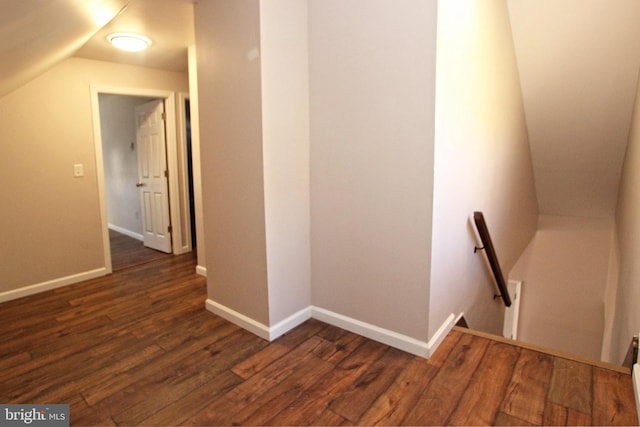 corridor with dark wood-type flooring and vaulted ceiling