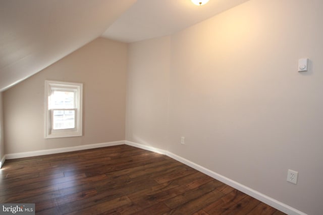 additional living space with vaulted ceiling and dark hardwood / wood-style flooring