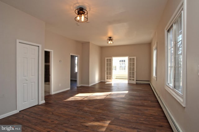 spare room with baseboard heating and dark hardwood / wood-style flooring