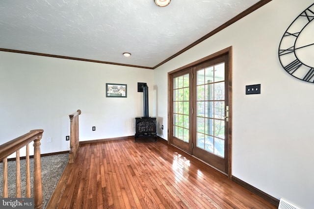 interior space with ornamental molding, wood-type flooring, and a wood stove