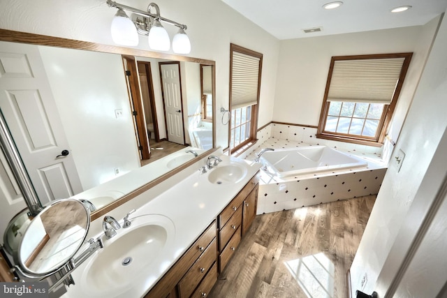 bathroom featuring vanity, hardwood / wood-style floors, and a relaxing tiled tub