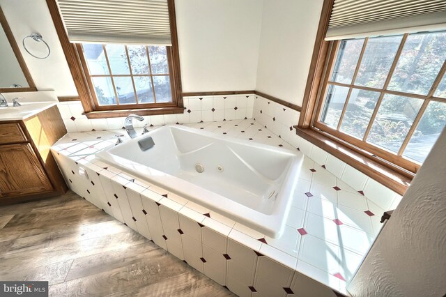 bathroom featuring vanity, a relaxing tiled tub, and hardwood / wood-style floors