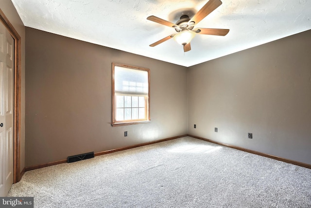 carpeted empty room featuring ceiling fan and a textured ceiling