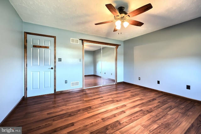 unfurnished bedroom featuring dark wood-type flooring, a textured ceiling, a closet, and ceiling fan