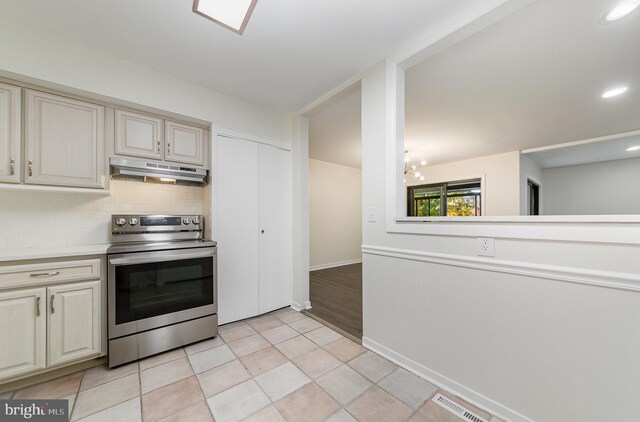 kitchen with a chandelier, cream cabinetry, backsplash, and electric stove