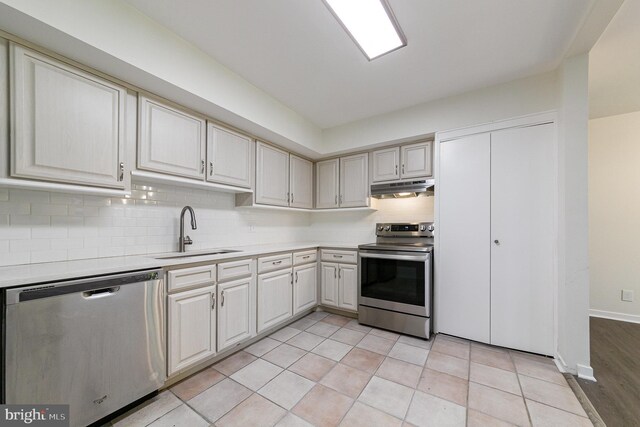 kitchen featuring sink, appliances with stainless steel finishes, decorative backsplash, and light tile patterned flooring