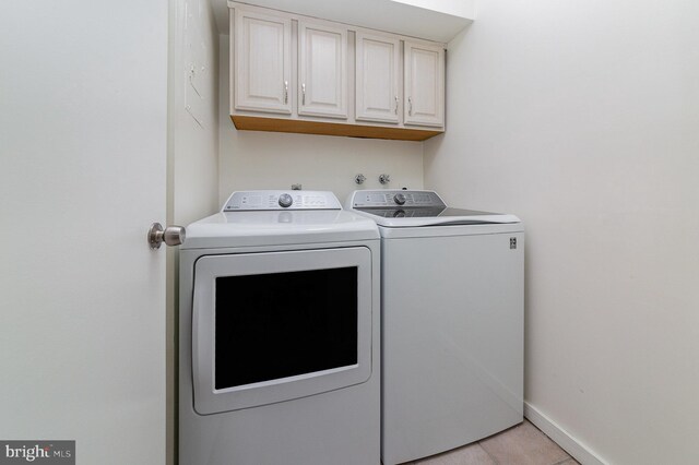 washroom with washing machine and clothes dryer and cabinets