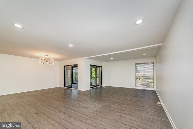 unfurnished room featuring a healthy amount of sunlight, dark hardwood / wood-style flooring, and a chandelier