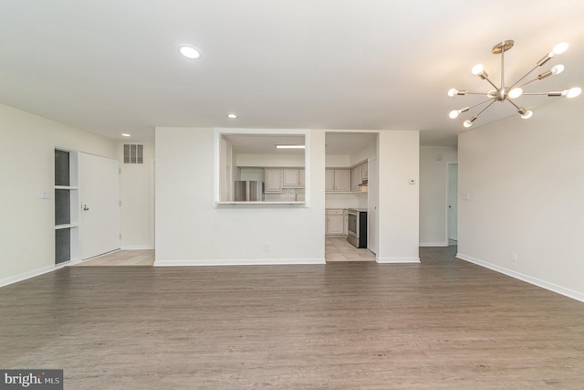 unfurnished living room featuring an inviting chandelier and light wood-type flooring