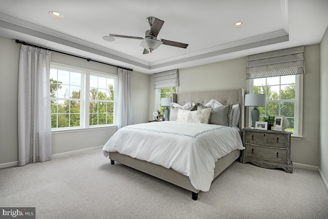 carpeted bedroom with ornamental molding, a raised ceiling, multiple windows, and ceiling fan