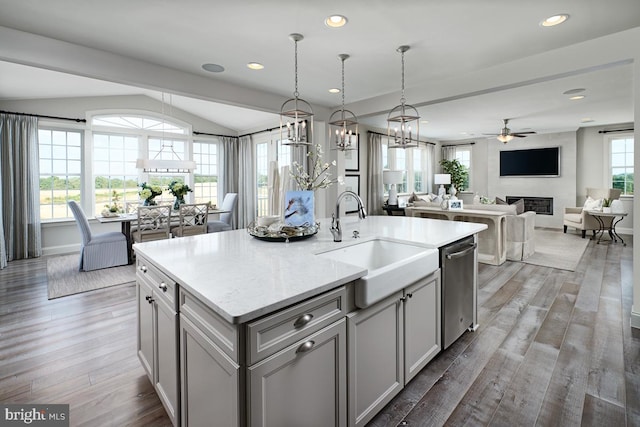 kitchen with sink, pendant lighting, dark hardwood / wood-style floors, and a kitchen island with sink