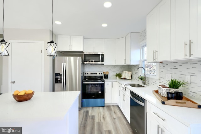 kitchen featuring light wood-type flooring, white cabinetry, hanging light fixtures, and stainless steel appliances