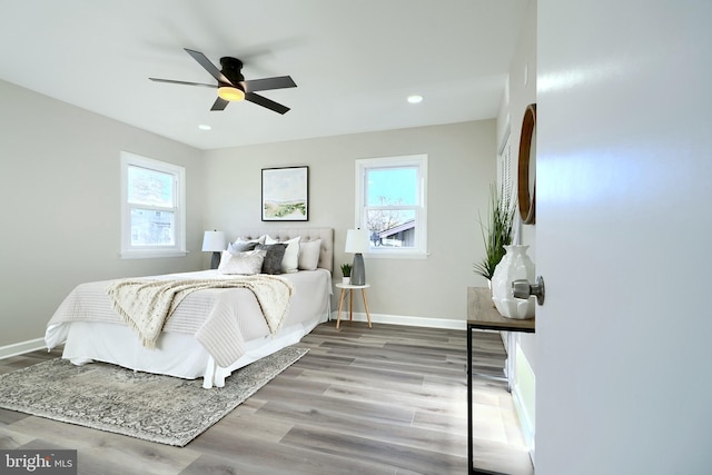 bedroom with ceiling fan, multiple windows, and light hardwood / wood-style floors