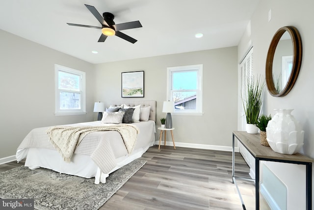 bedroom with hardwood / wood-style floors, ceiling fan, multiple windows, and a closet