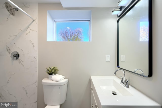 bathroom with tiled shower, toilet, and vanity