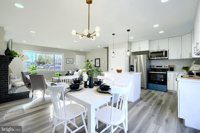 dining space with a chandelier, light hardwood / wood-style floors, and a fireplace