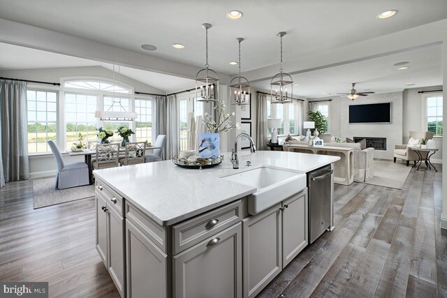 kitchen with sink, a kitchen island with sink, decorative light fixtures, and dark hardwood / wood-style floors