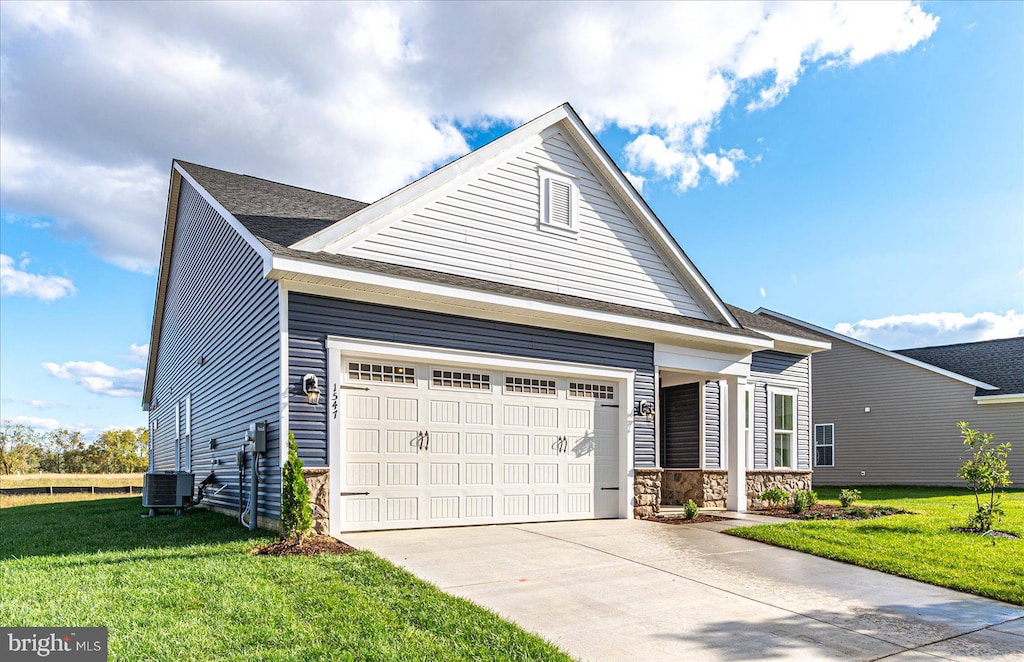 view of front of property with a front yard, a garage, and central AC unit