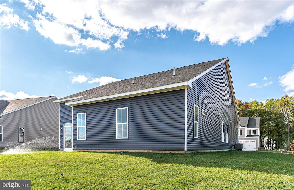 rear view of property featuring a lawn and a garage